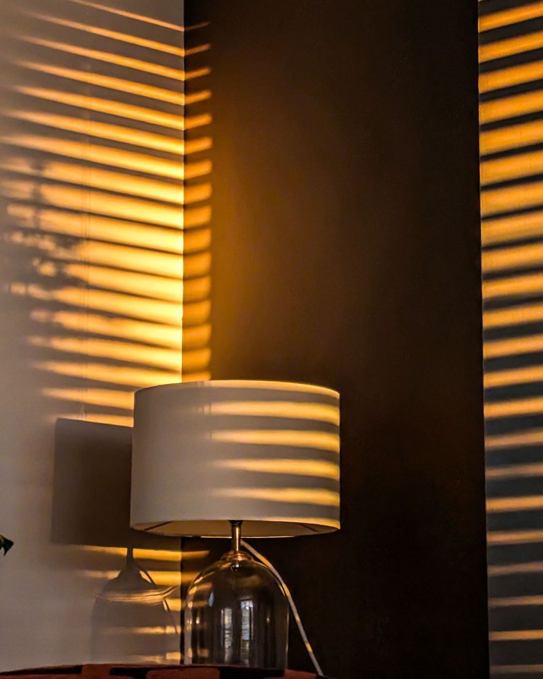 The LUMI lamp being read: a drum-shade lamp in striped window light
