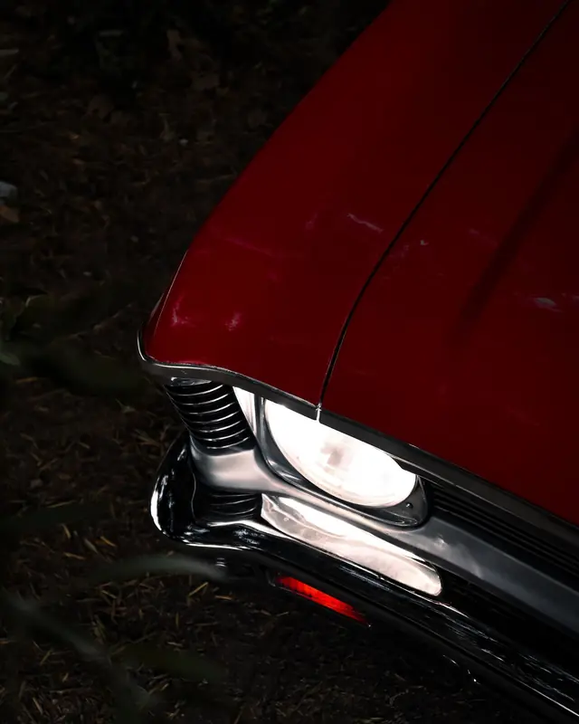 The chrome headlight of a red classic car