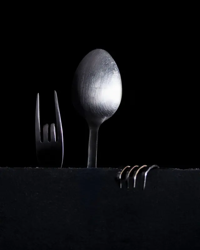 A spoon and forks emerging from black