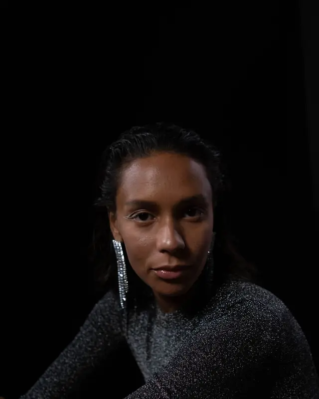 A woman in a glistening dress wearing long earrings