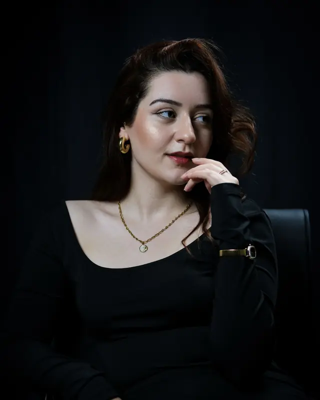 A woman in a black dress wearing gold jewellery