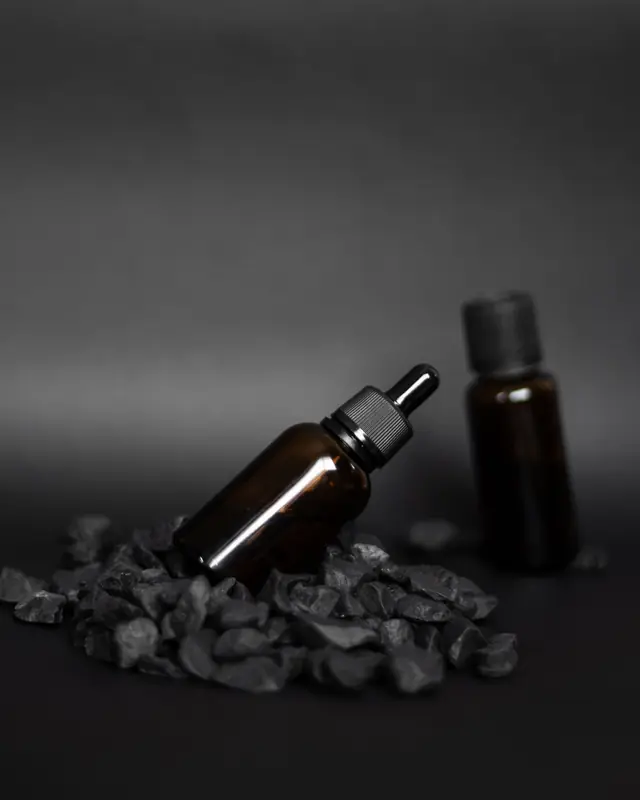 Amber dropper bottles on dark gravel